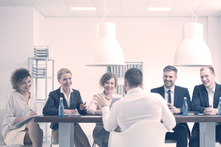 A panel interviews a candidate. Group of young business people sit across the table from a candidate.