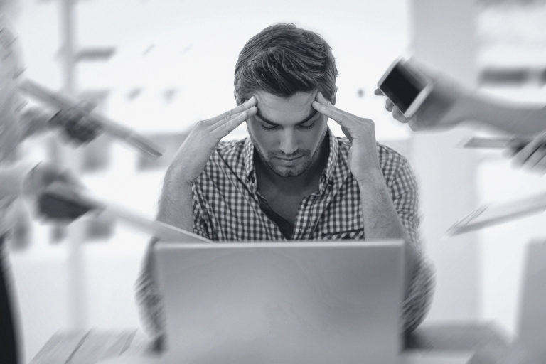 Casual businessman sits with head in hands over stress.