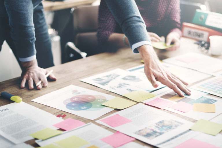 Business people work on process with papers scattered on a conference table.