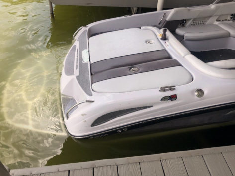 A ski boat sits in the water at a dock
