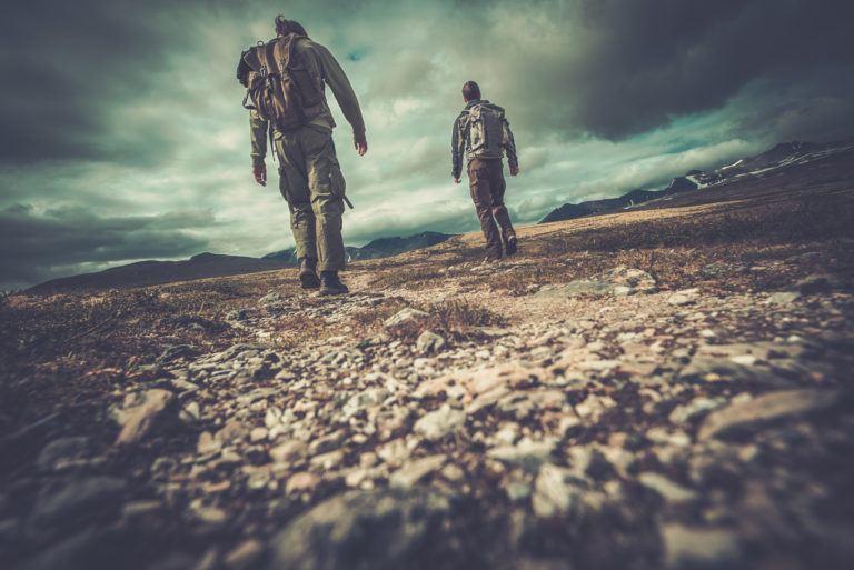 Weary hikers walk in a valley with mountains in sight