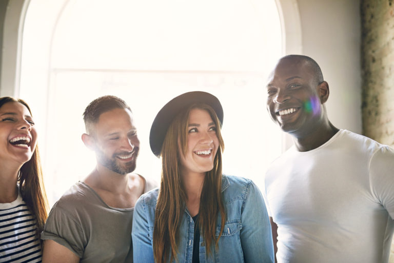 A group of young happy coworkers gather close for a photo