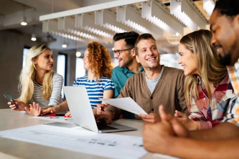 Young professionals talking amongst each other at a meeting table.