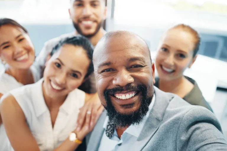 Five employees standing closely to one another and smiling.
